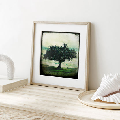 Framed artwork of a tree on a wooden surface with decorative items.